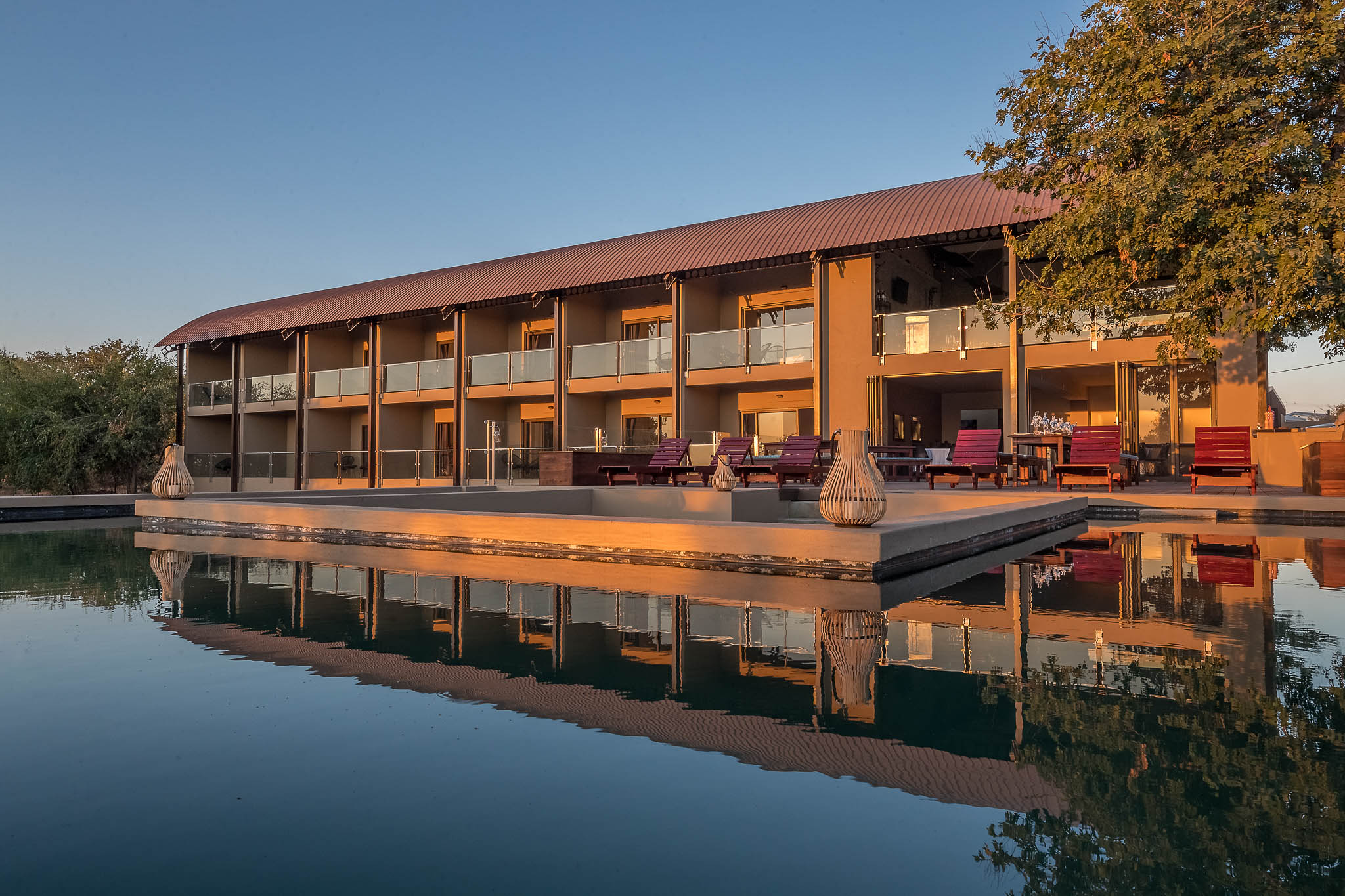 Pangolin Chobe Hotel reflected in its pool at dusk
