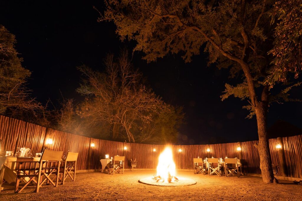 Kapama Buffalo Camp boma with a central fire and tables set for dinner