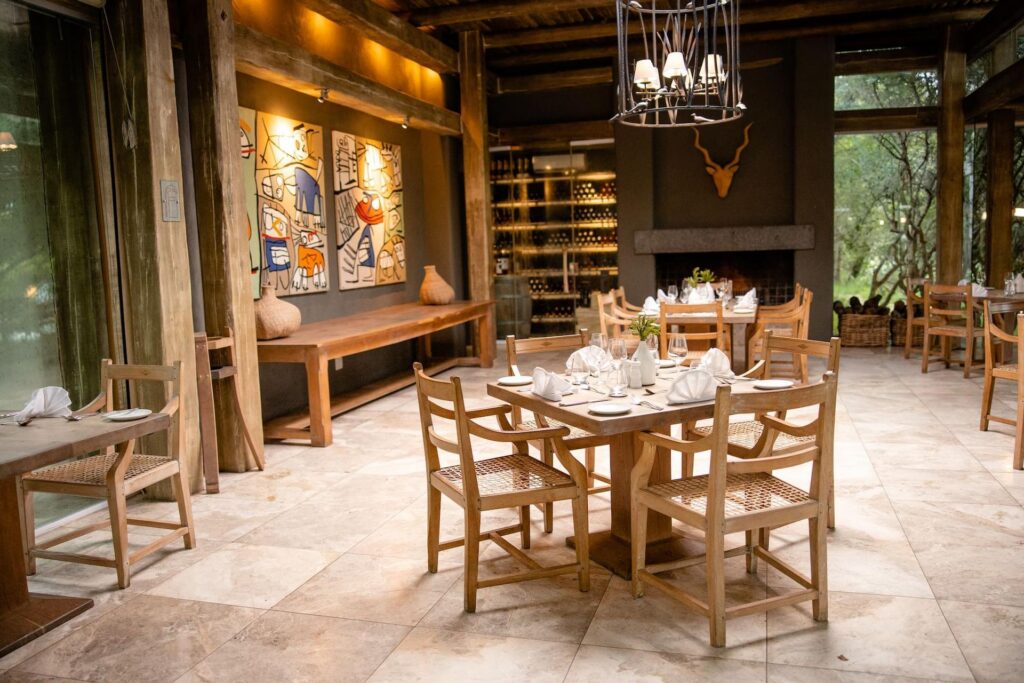 Kapama Karula dining room with a fireplace, wine wall and set tables