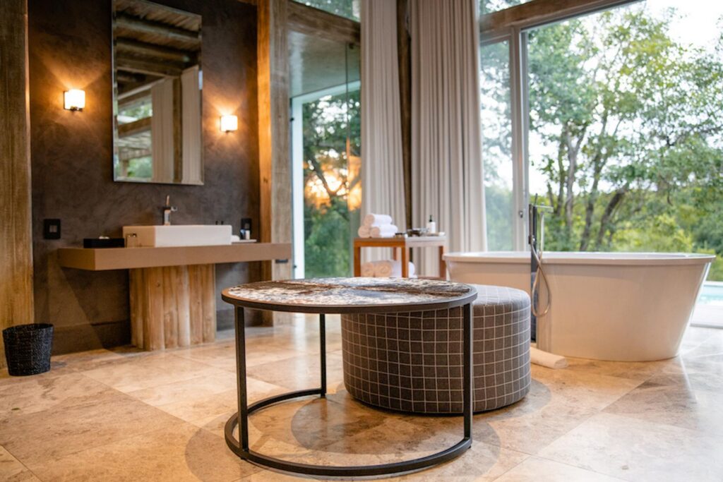 Kapama Karula villa bathroom with a freestanding bath and floor-to-ceiling windows onto the bush
