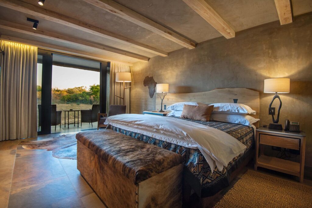 Kapama River Lodge Deluxe Suite bedroom opening onto a patio and bush view