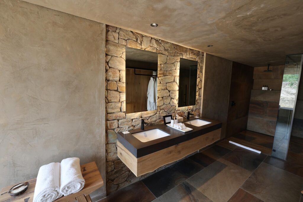 Kapama River Lodge Deluxe Suite bathroom with double basins and a stone feature wall