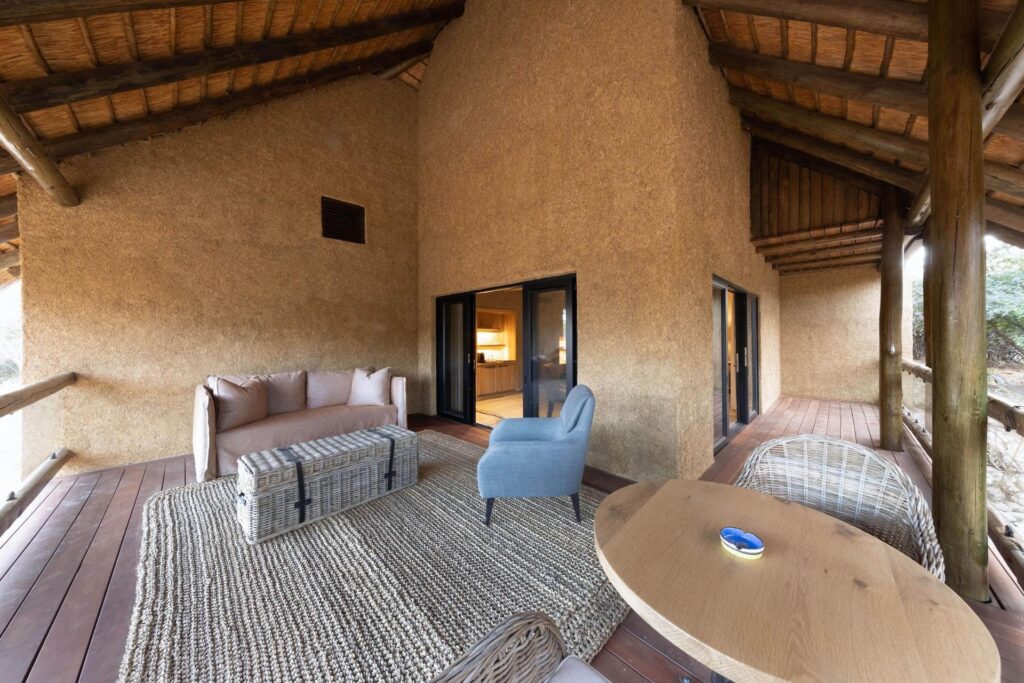 Covered balcony with a sofa and chairs at a Kapama River Lodge Royal Suite