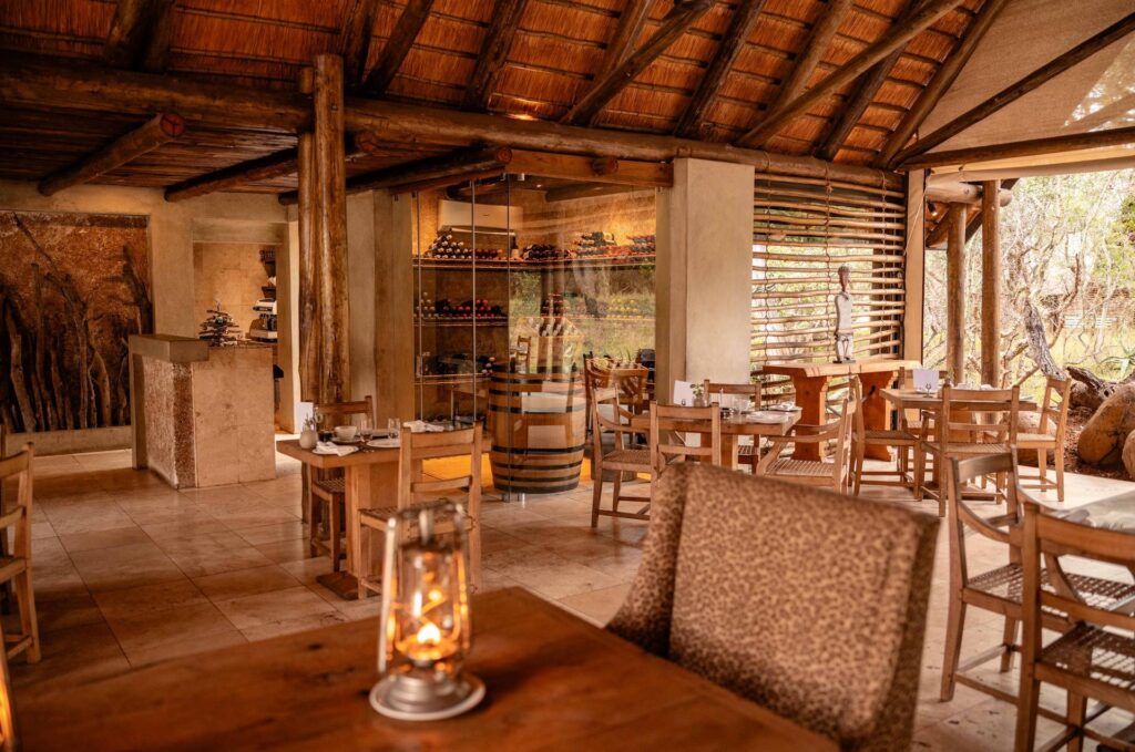 Kapama Southern Camp dining room with timber tables and a wine display