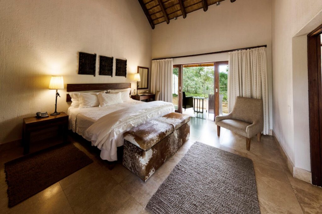 Kapama Southern Camp Standard Suite bedroom with doors open to the bush