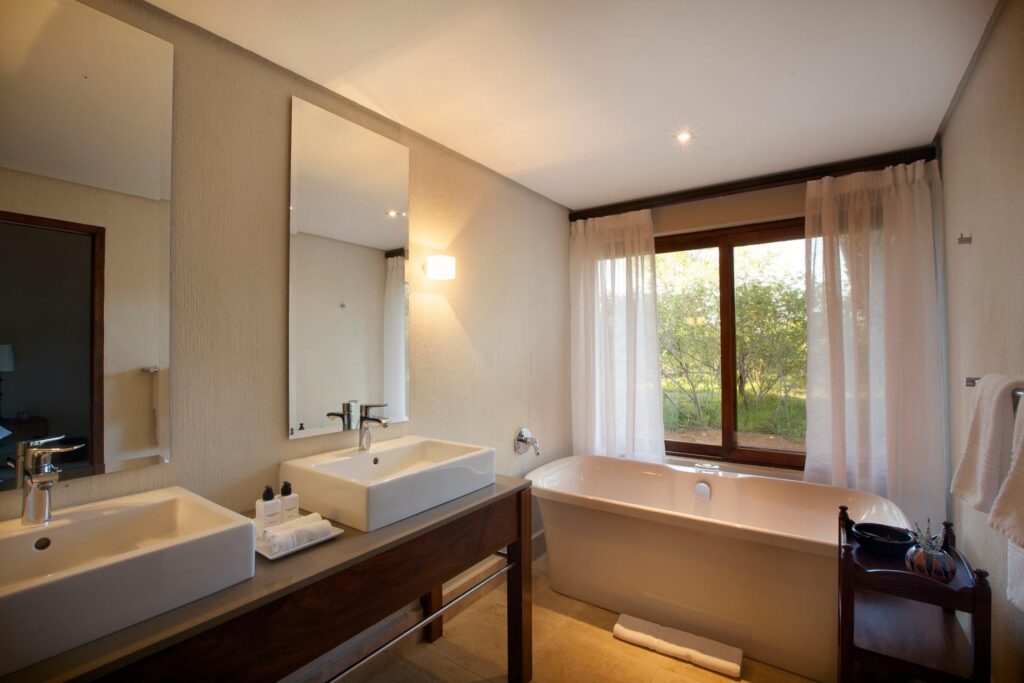 Kapama Southern Camp Standard Suite bathroom with double basins and a bath