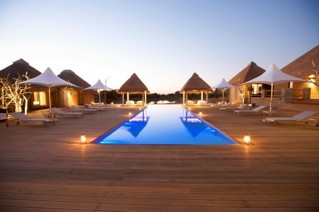 Kapama Wellness Centre pool and thatched treatment rooms at dusk